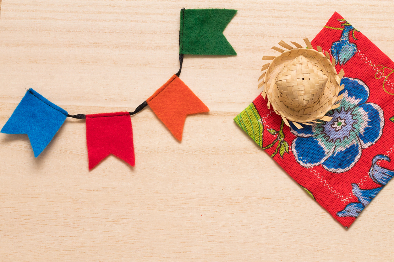 Traditional party supplies for the typical brazilian festival "Festa Junina" (June Festival) background. Cute handmade colorful flags, tiny hat and citra fabric (brazilian "Chita" fabric). Handmande felt items