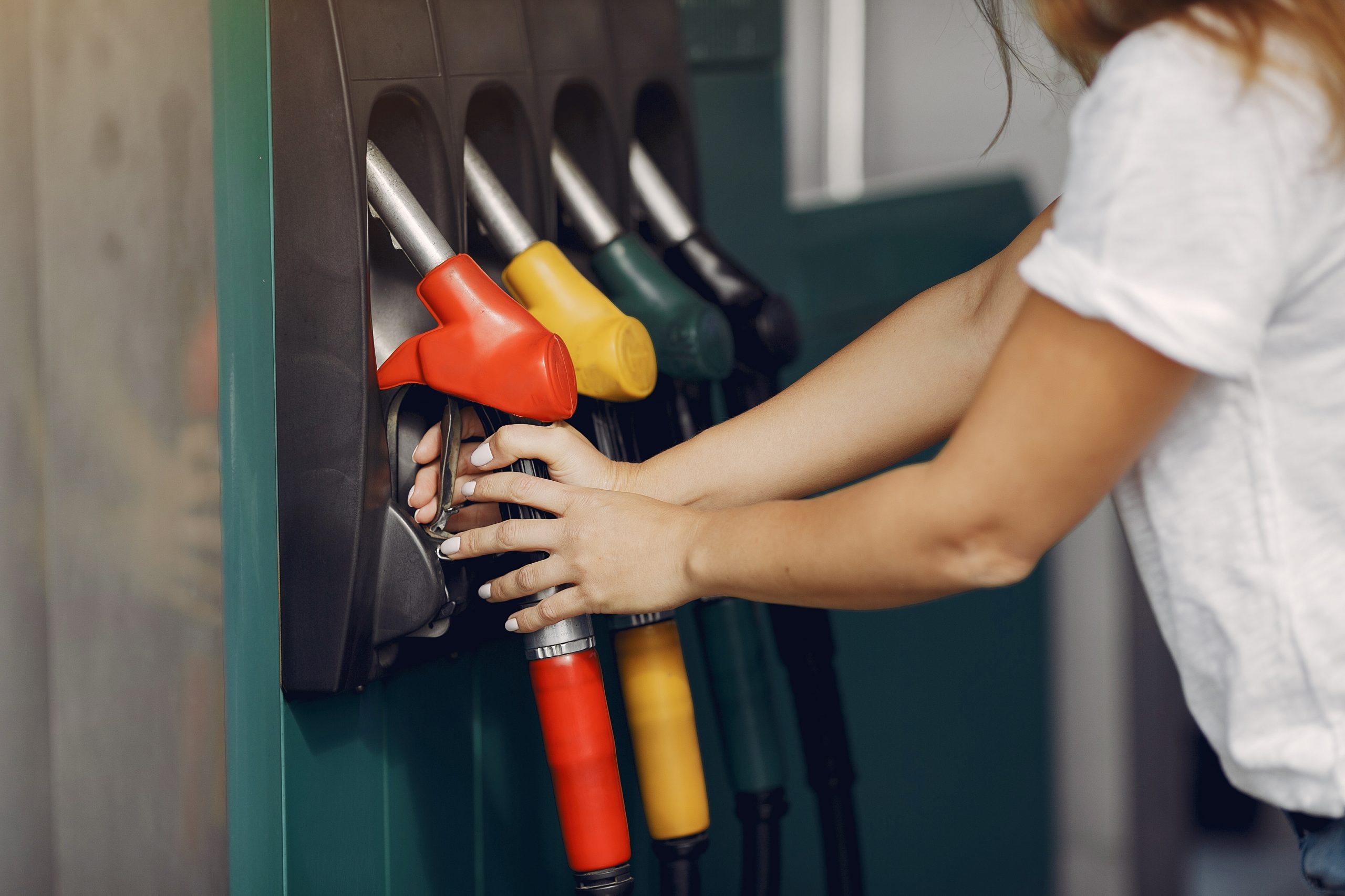 Woman on a gas station. Lady in a white t-shirt. Woman near the car.