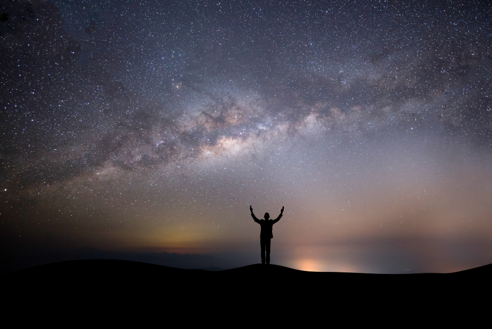 silhouette-successful-man-on-the-top-of-the-hill-on-a-background-with-stars