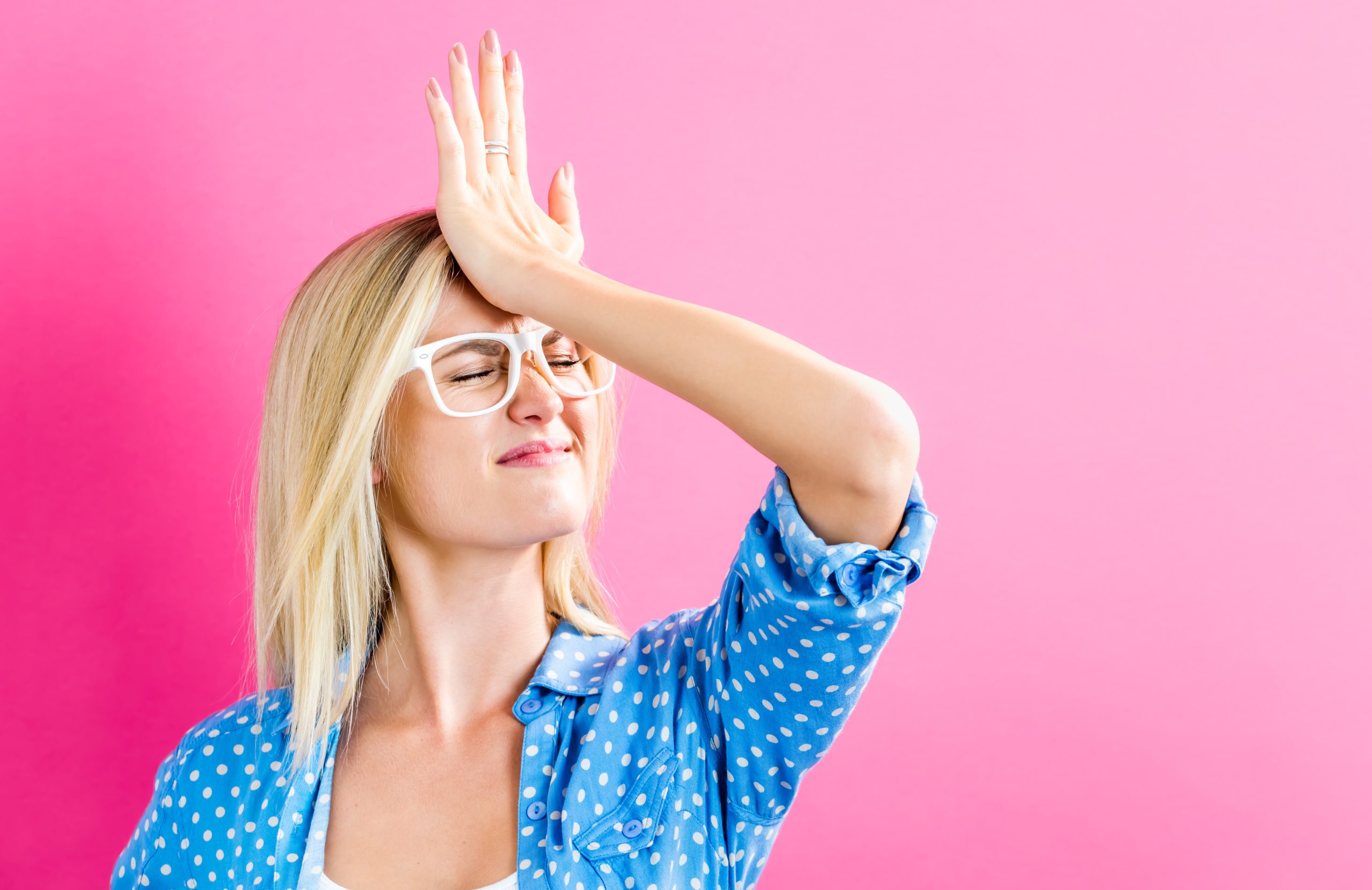 Young woman making a mistake on a pink background