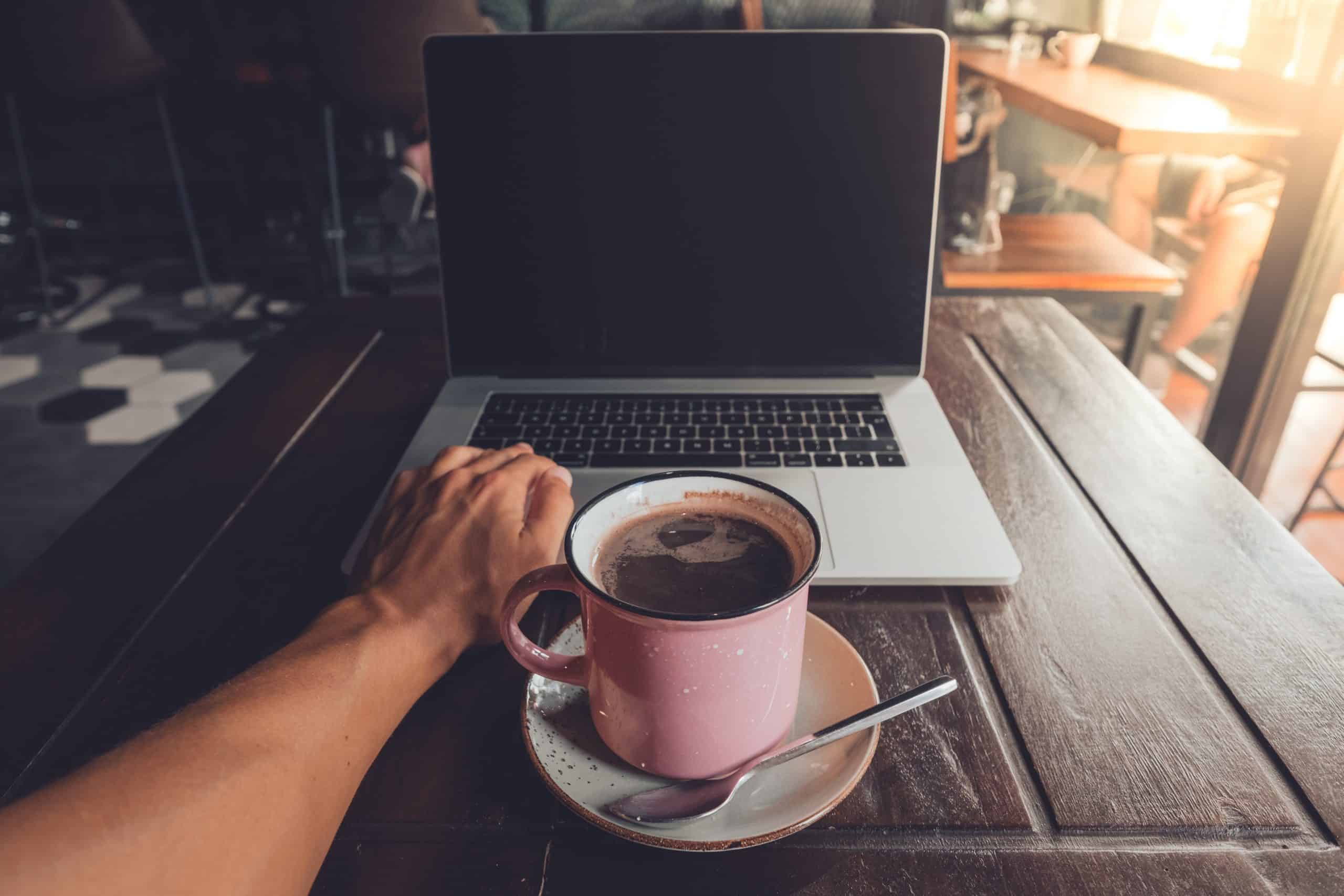 Nómada digital trabajando en una cafetería con su ordenador y