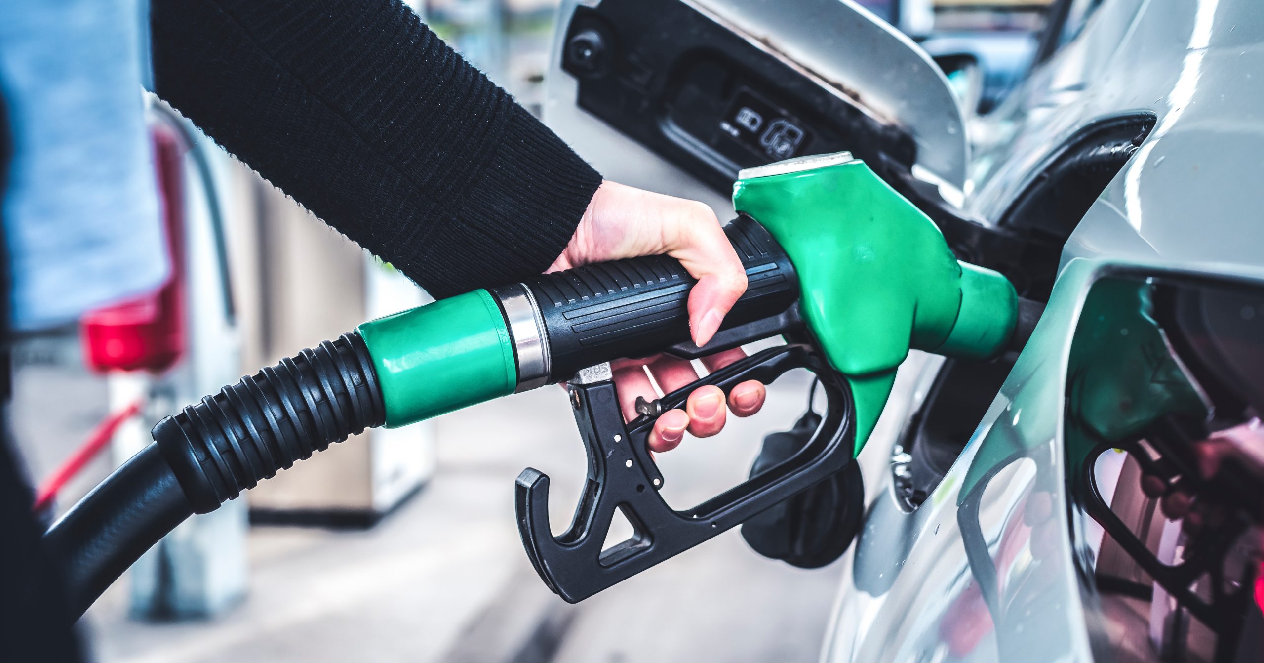 Woman pumping gasoline fuel in car at gas station.