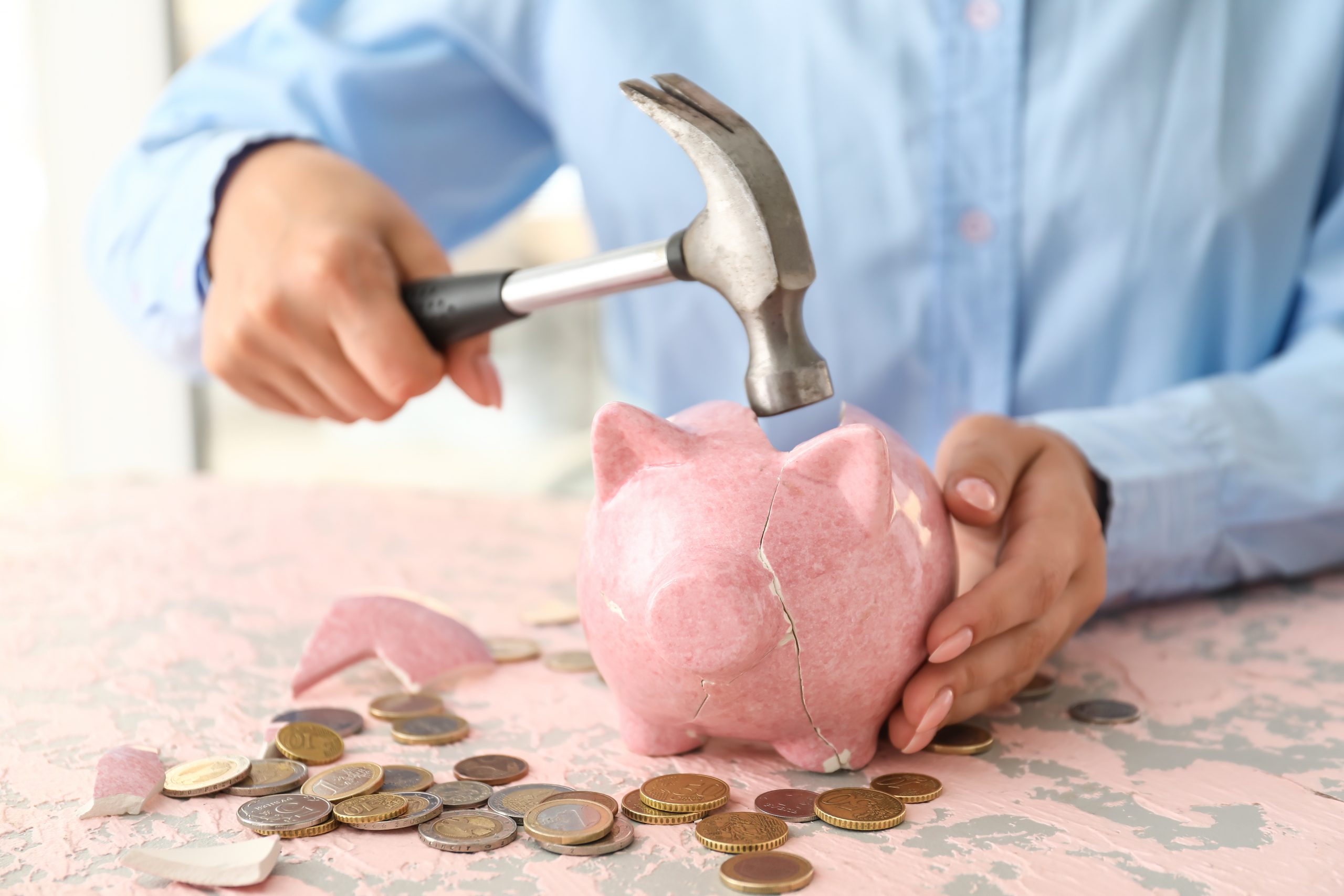 Woman breaking piggy bank at table