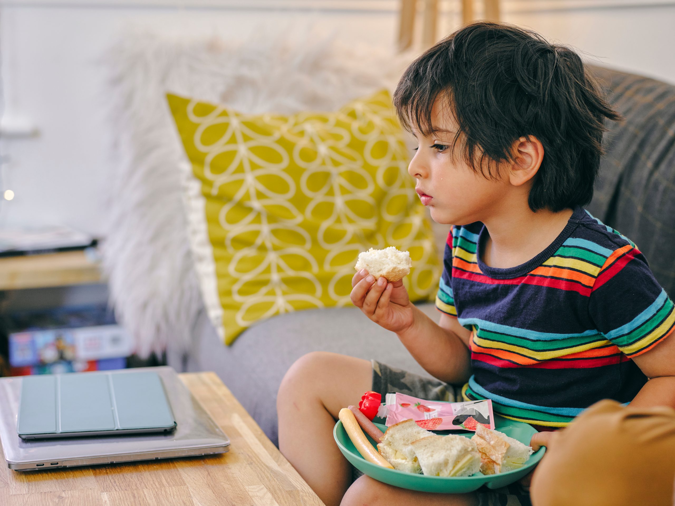 Boy (4-5) sitting on sofa and eating