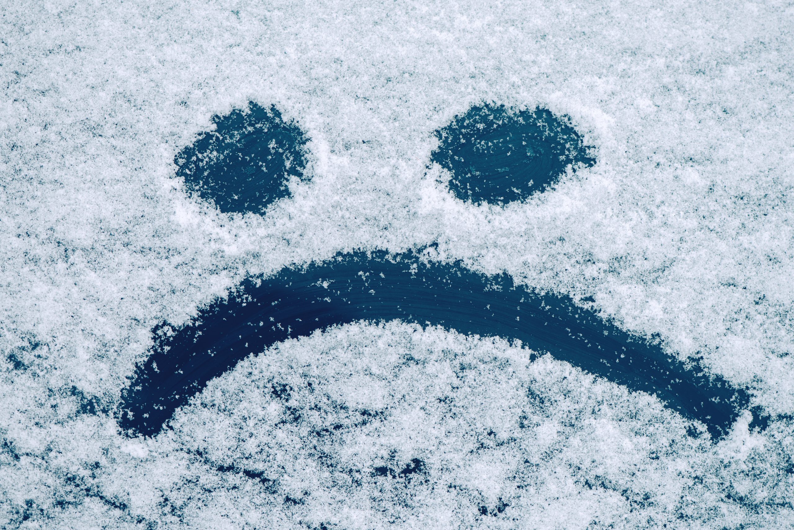 Sad smiley emoticon face drawn on snow covered glass, winter season sadness concept