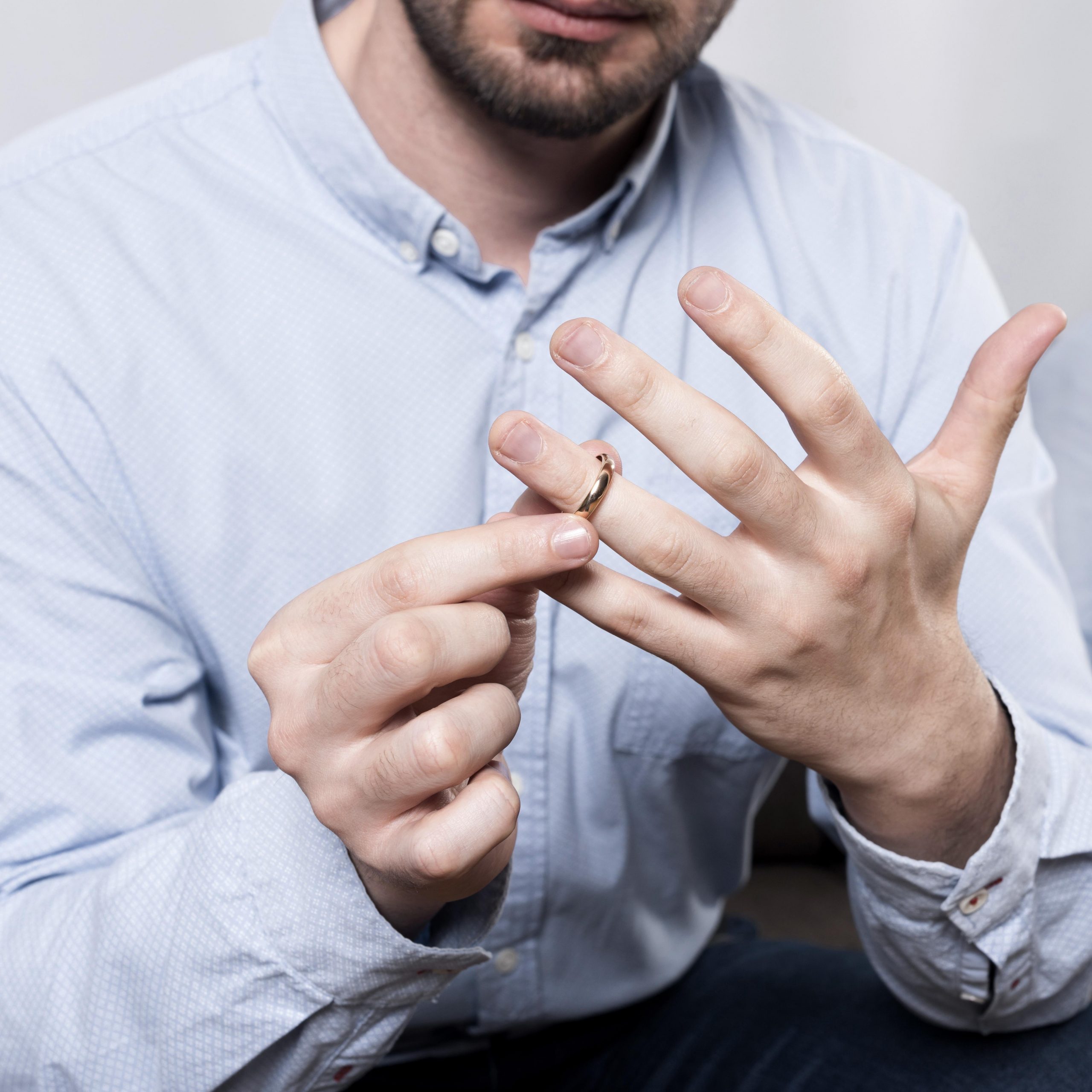 close-up-man-taking-wedding-ring-off-finger